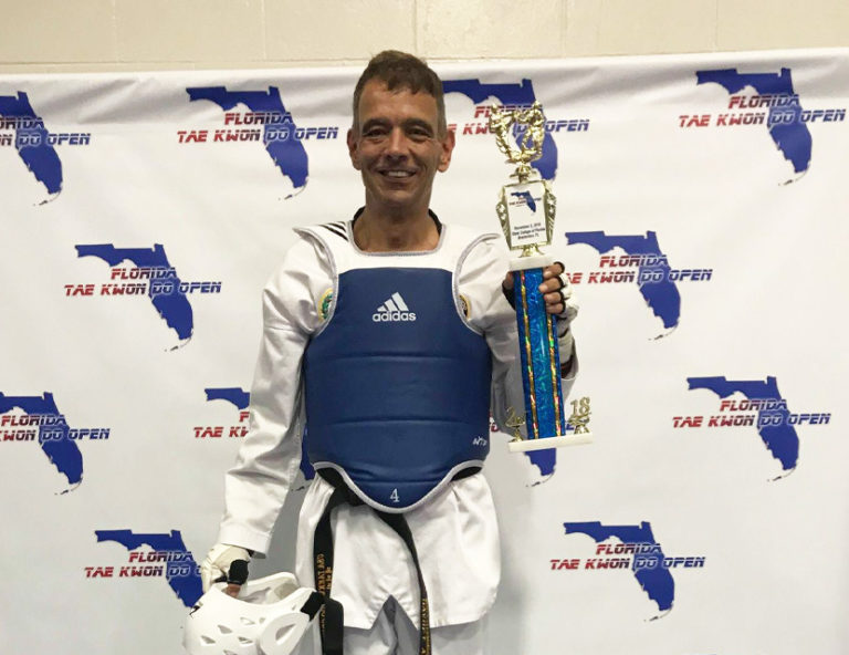 man holding a taekwondo trophy